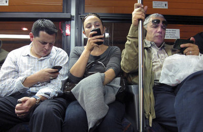 Commuters use their smartphones as they ride in a bus leaving Manhattan through the Lincoln Tunnel in New York