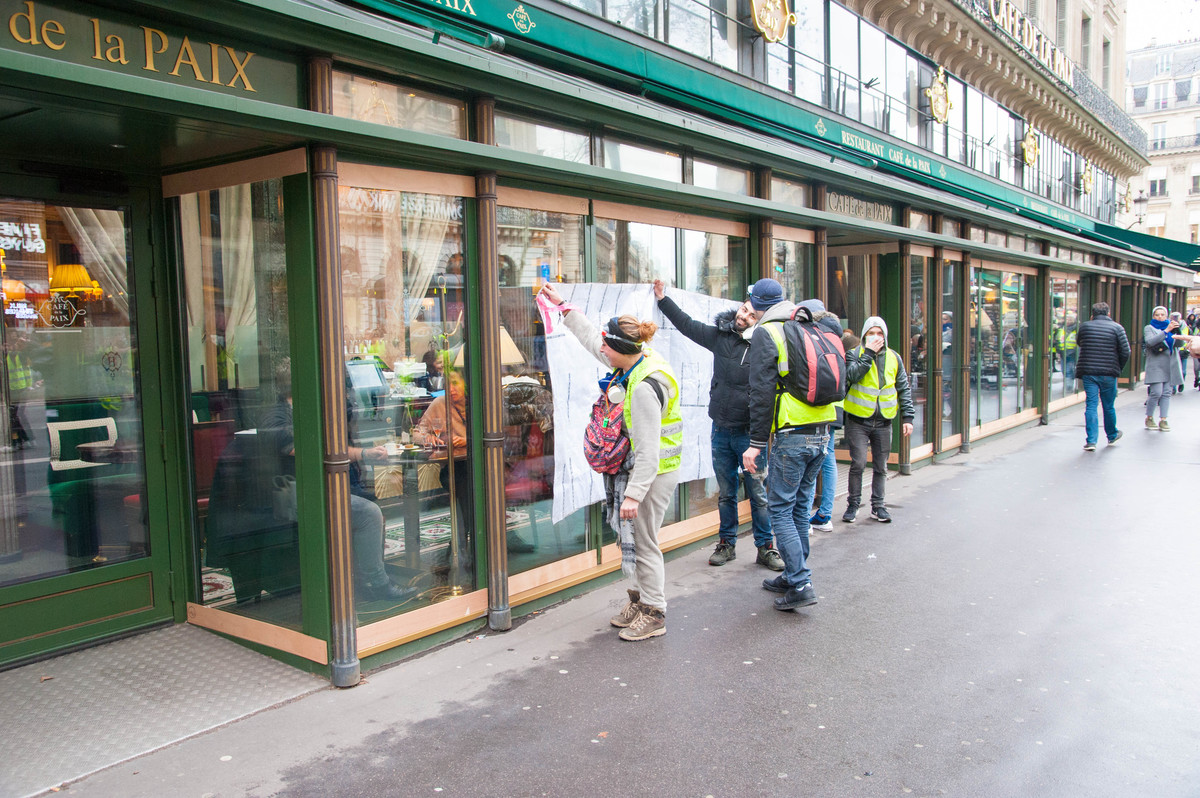 Les manifestants tentent de sensibiliser les personnes attablées au Café de la Paix, place de l'Opéra en leur montrant les photos des blessés. Sans succès. - © Reflets