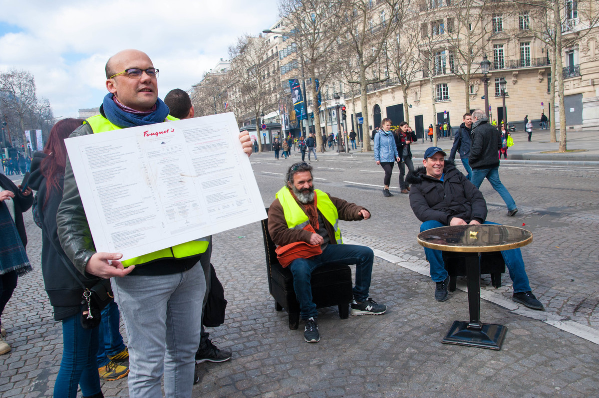 Buvette improvisée au milieu des Champs. Le Fouquet's a été dévasté. Ce manifestant a dû ramasser une carte qui traînait. - © Reflets