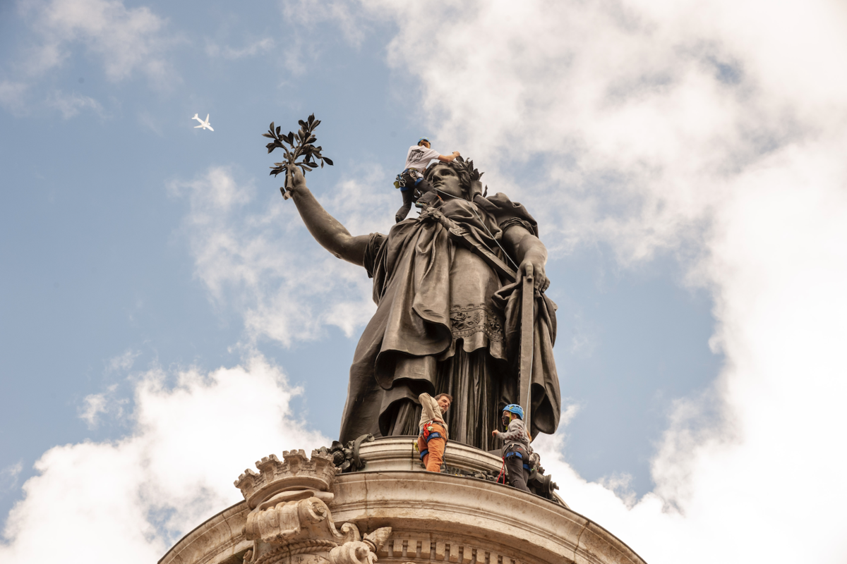 Des "alpinistes" vont rhabiller la statue. Un avion passe au loin, indifférent. - © Reflets
