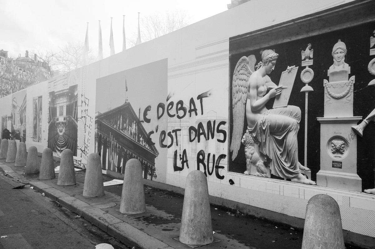 Clin d'oeil au grand débat national d'Emmanuel Macron sur la palissade devant l'Assemblée - © Reflets