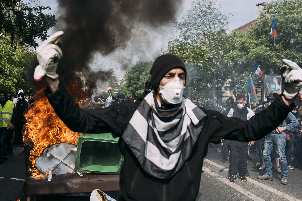 Un manifestant devant du mobilier urbain en feu lors du traditionnel défilé pour la Fête du Travail.  - © Denis Meyer