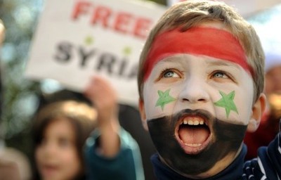 Child in a demonstration with face painted with the Syrian flag, chanting